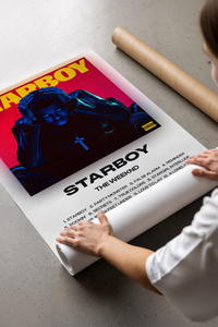 Hands unrolling the Starboy music poster revealing the blue portrait and red background with track listing