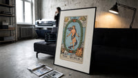 The World tarot card figure print in a slim black frame leaning on a dark sofa in a concrete print studio