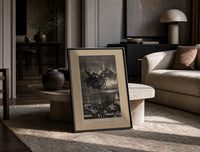 Santa Claus in reindeer sleigh over rooftops print in a black frame leaning on a travertine table in a sunlit lounge