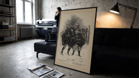 Two children print in a slim black frame leaning on a dark sofa in a concrete print studio
