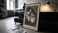 Two young children in nightgowns print in a slim black frame leaning on a dark sofa in a concrete print studio