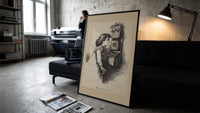 Girl speaking into wall telephone print in a slim black frame leaning on a dark sofa in a concrete print studio