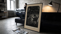 Santa Claus seated before a fireplace print in a slim black frame leaning on a dark sofa in a concrete print studio