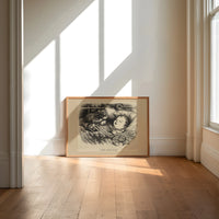 Santa Claus watching a sleeping child print in an oak frame on a sunlit wood floor beneath tall window light