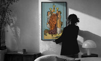 Three of Cups print in a slim black frame being hung on a sunlit wall in a monochrome room