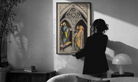 Three of Pentacles print in a slim black frame being hung on a sunlit wall in a monochrome room
