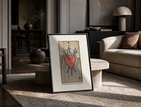 Heart pierced by three swords print in a black frame leaning on a travertine table in a sunlit lounge