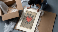 Heart pierced by three swords framed print being unpacked from protective bubble wrap and a box