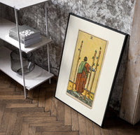 Figure holding staffs facing sea poster in a black frame leaning beside a shelf in a raw-plaster loft