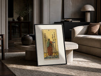 Figure holding staffs facing sea print in a black frame leaning on a travertine table in a sunlit lounge