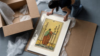 Figure holding staffs facing sea framed print being unpacked from protective bubble wrap and a box