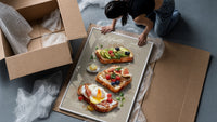 Three Toasts with Egg, Avocado and Fig framed print being unpacked from protective bubble wrap and a box