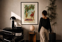 Toy Soldier Merry Christmas print in a black frame on a sunlit plaster wall, a person looking on beside a mushroom lamp