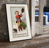 Boy dragging Christmas tree on sled print in a black frame leaning beside a vintage door on parquet