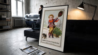Boy dragging Christmas tree on sled print in a slim black frame leaning on a dark sofa in a concrete print studio