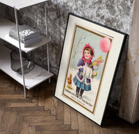 Girl in winter coat holding toys poster in a black frame leaning beside a shelf in a raw-plaster loft