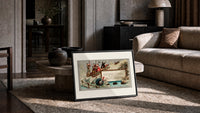 Children sledding downhill past turkeys print in a slim black frame leaning on a travertine coffee table