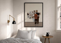 Black Couple at a Gallery Wall print in a black frame above a bed with striped linens