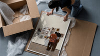 Black Couple at a Gallery Wall framed print being unpacked from protective bubble wrap and a box