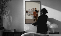 Black Couple at a Gallery Wall print in a slim black frame being hung on a sunlit wall in a monochrome room