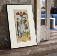 Two people toasting golden cups print in a black frame leaning beside a vintage door on parquet