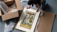 Two people toasting golden cups framed print being unpacked from protective bubble wrap and a box
