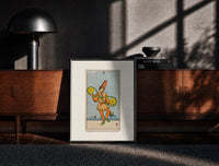 Black-framed Two of Pentacles tarot figure print on a moody console with designer coffee-table books