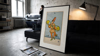 Two of Pentacles tarot figure print in a slim black frame leaning on a dark sofa in a concrete print studio