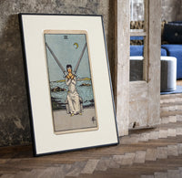 Blindfolded woman holding two crossed swords print in a black frame leaning beside a vintage door on parquet