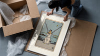 Blindfolded woman holding two crossed swords framed print being unpacked from protective bubble wrap and a box