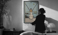 Two of Swords print in a slim black frame being hung on a sunlit wall in a monochrome room