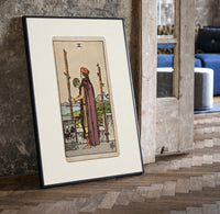 Man holding globe and staff print in a black frame leaning beside a vintage door on parquet