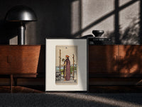 Black-framed Man holding globe and staff print on a moody console with designer coffee-table books