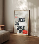 Under Construction typographic wall art poster leaning against wall in modern living room