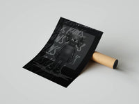 Standing black KAWS companion on dark graffiti backdrop, rolled print resting next to a cardboard tube on gray