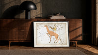 Camelopardalis constellation giraffe with figures print in a black frame leaning against a walnut console in lamplight