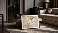 Unicorn and dog constellation illustration print in a slim black frame leaning on a travertine coffee table