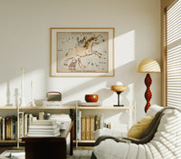 Unicorn and dog constellation illustration print in an oak frame above a mid-century book console with a vintage radio