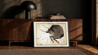 Taurus bull constellation chart print in a black frame leaning against a walnut console in lamplight