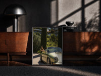 Black-framed Vintage Green 911 Targa at the Villa print on the floor in front of a dark wooden console