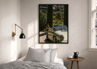 Vintage Green 911 Targa at the Villa print in a black frame above a bed with striped linens