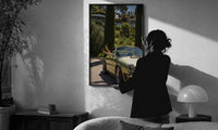 Vintage Green 911 Targa at the Villa print in a slim black frame being hung on a sunlit wall in a monochrome room