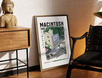 Brass-framed Vintage Macintosh computer with plants print leaning in a warm styled corner by a sculpture