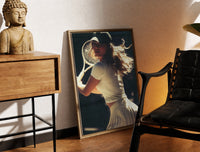 Brass-framed vintage tennis serve print leaning in a warm styled corner by a sculpture