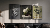 Floral still life triptych paintings triptych in three black frames on a grey wall above a leather sofa