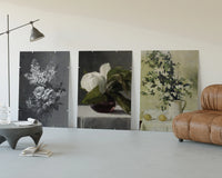 Floral still life triptych paintings three-panel set displayed beside a brown leather sofa