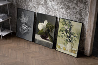 Floral still life triptych paintings set of three black-framed prints leaning against a raw-plaster wall