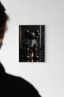 White-framed KAWS black companion reading poster on wall, silhouetted person visible in foreground