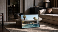 White 911 Desert Modern Pool House print in a black frame leaning on a rug beside a beige sofa