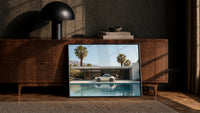 White 911 Desert Modern Pool House print in a black frame leaning against a walnut sideboard